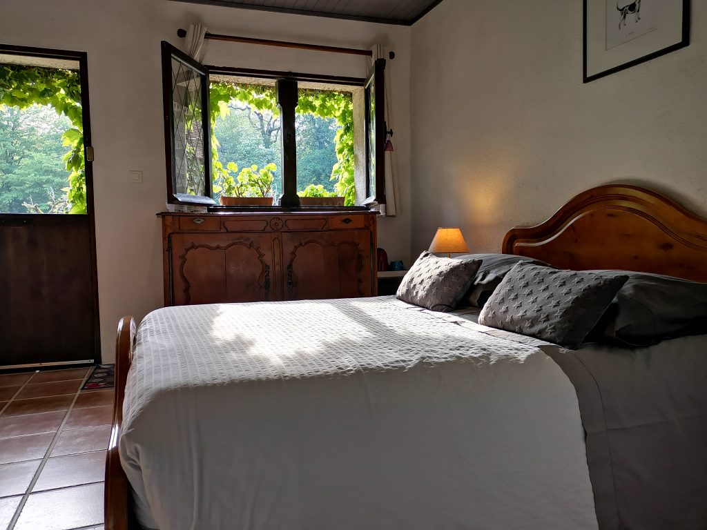 Lit double et fenêtre donnant sur les arbres dans la chambre n°2