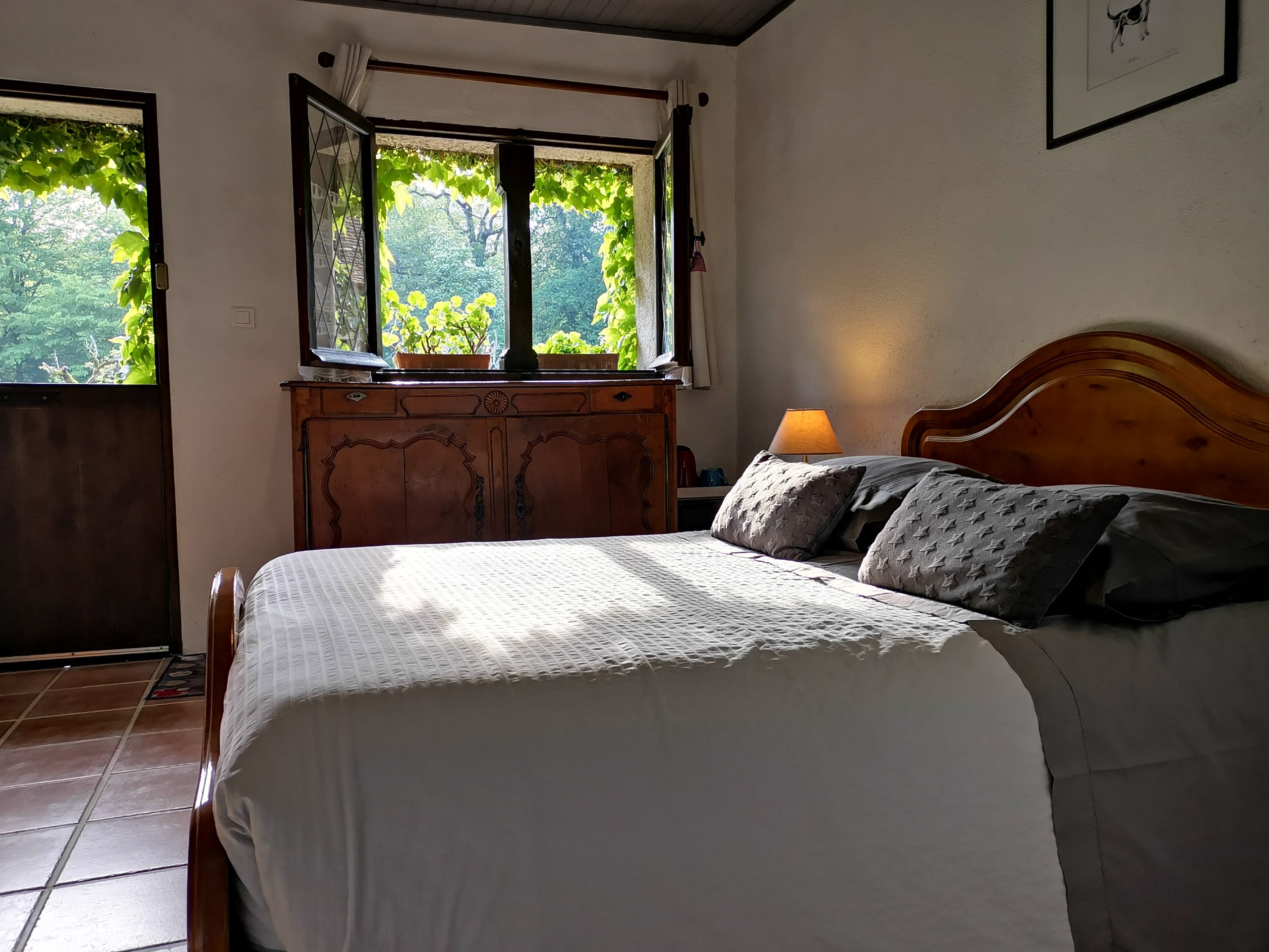 Lit double et fenêtre donnant sur les arbres dans la chambre n°2